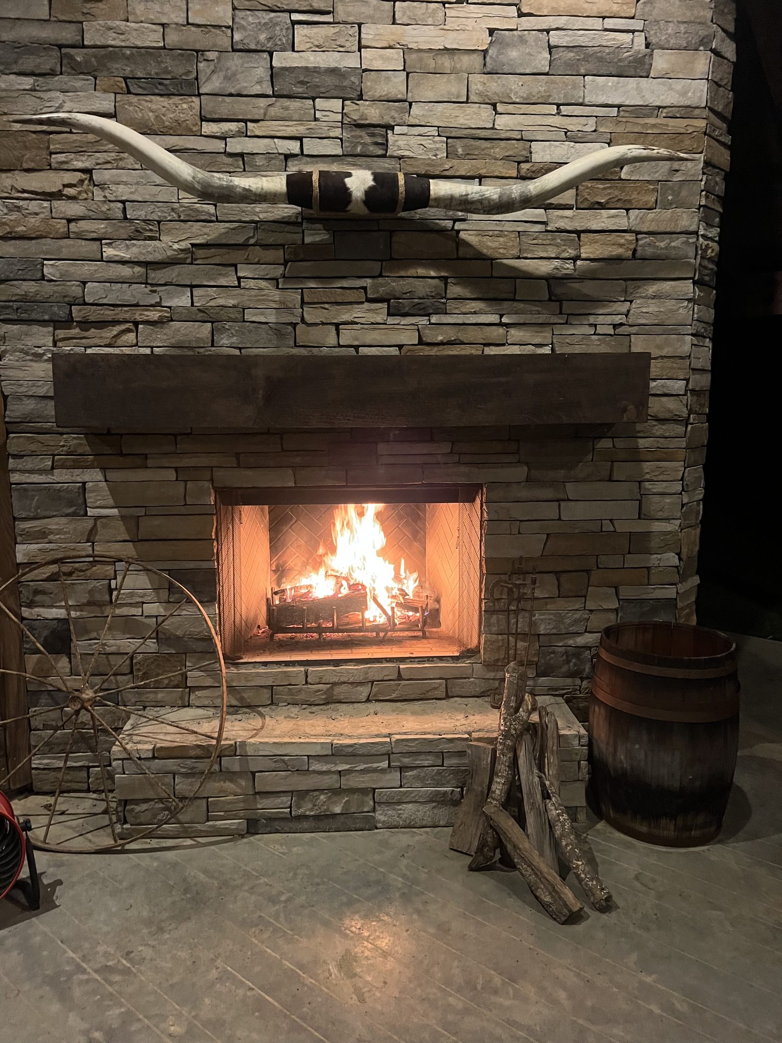 The stone fireplace lit at night with longhorn horns mounted above