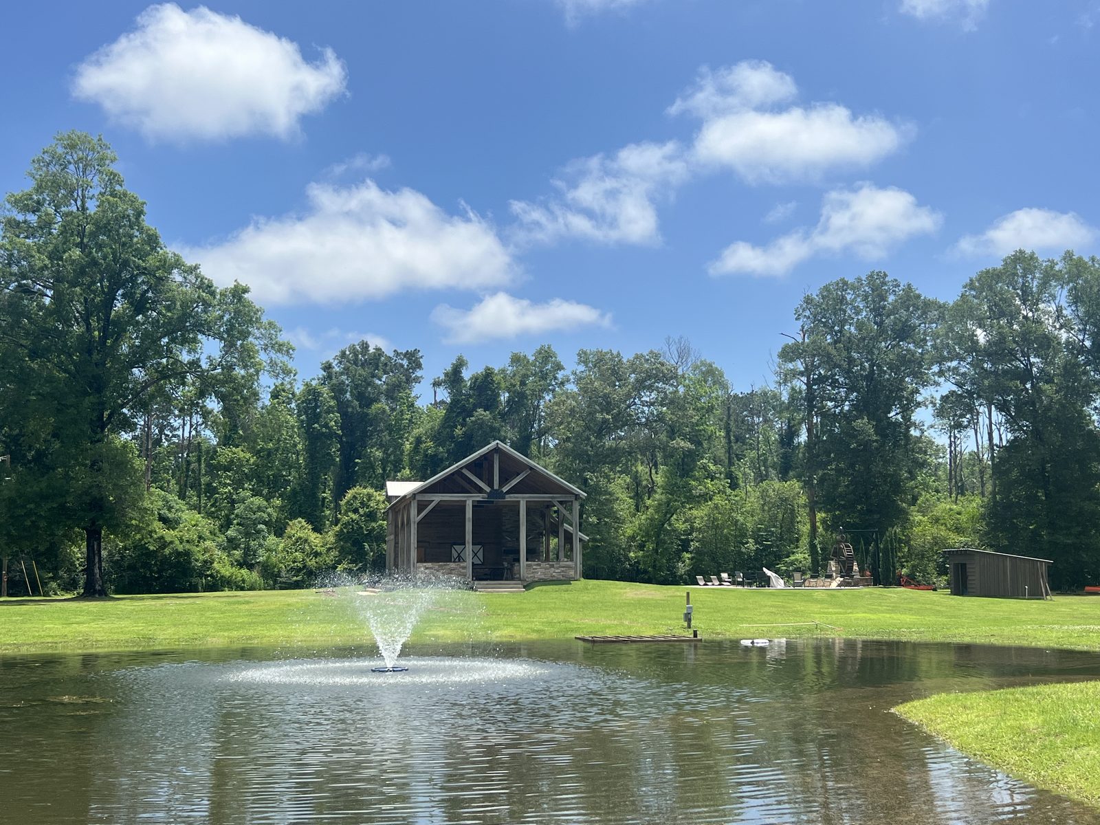 The barn and its open pavilion seen across the pond, fountain running